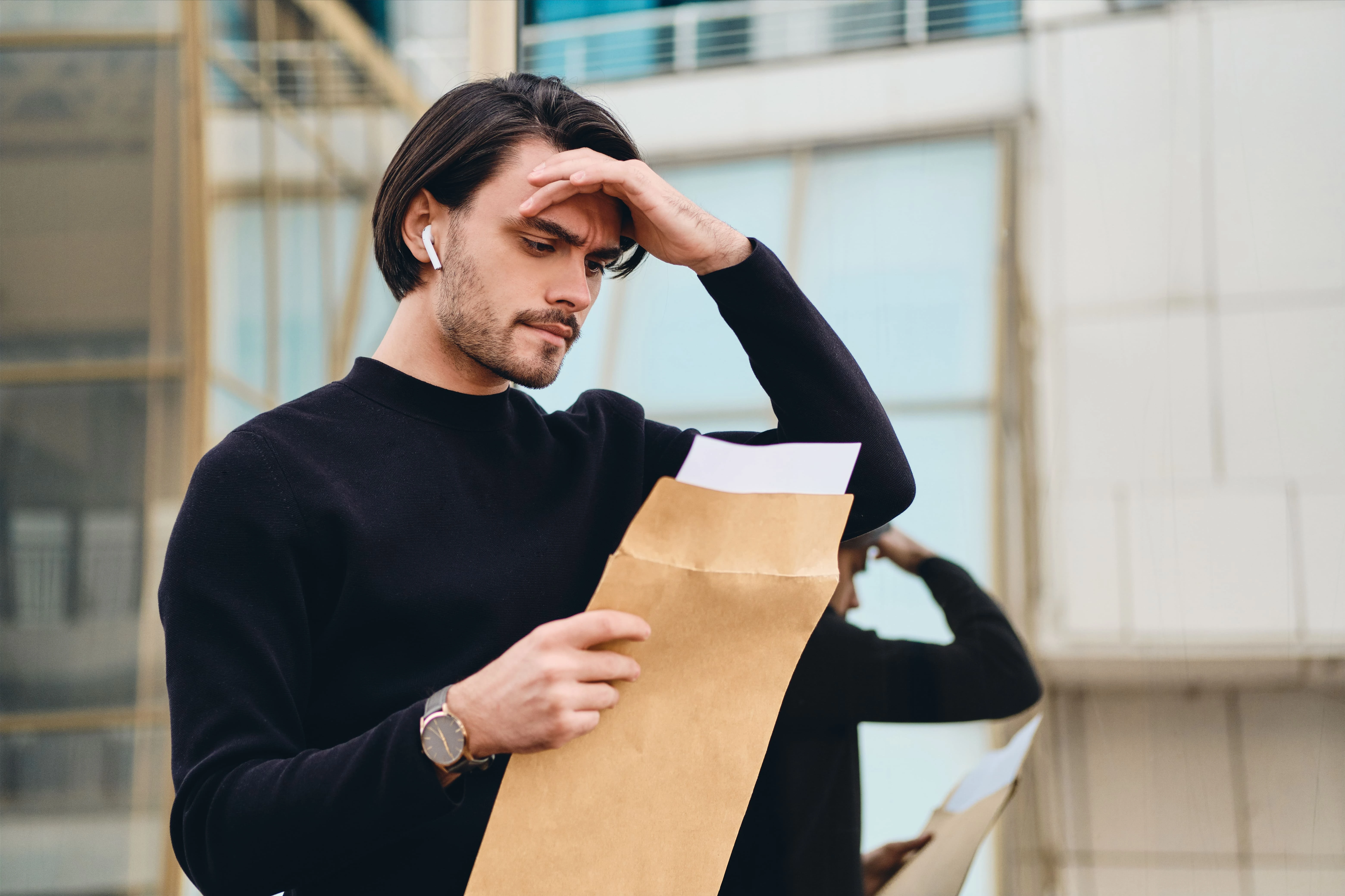 A man examines a paper while looking at his forehead, contemplating the end of EAD automatic extensions and new regulations.