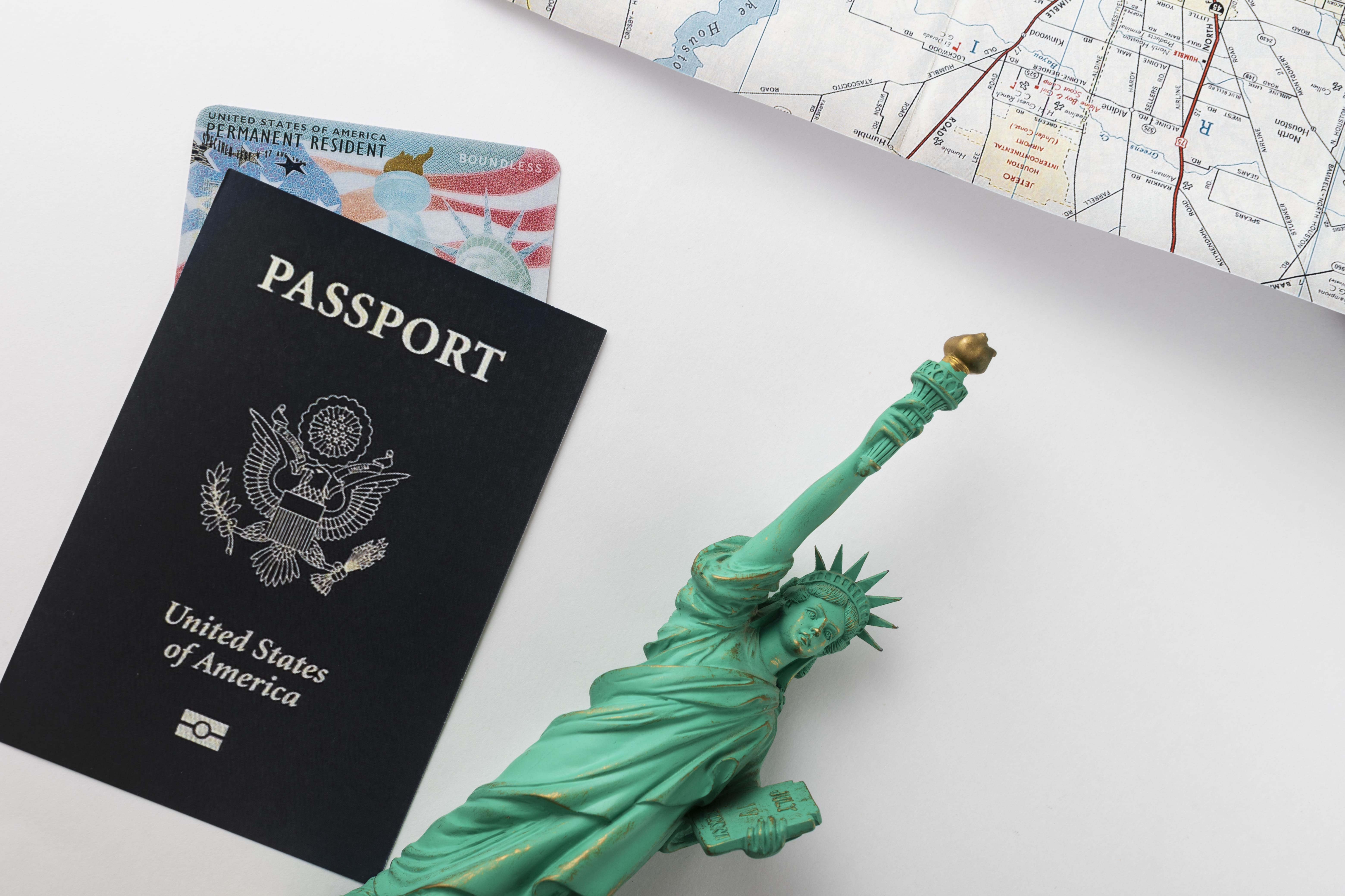 Una persona con pasaporte y tarjeta verde, que simboliza los pasos dados para eliminar las condiciones de residencia permanente.
