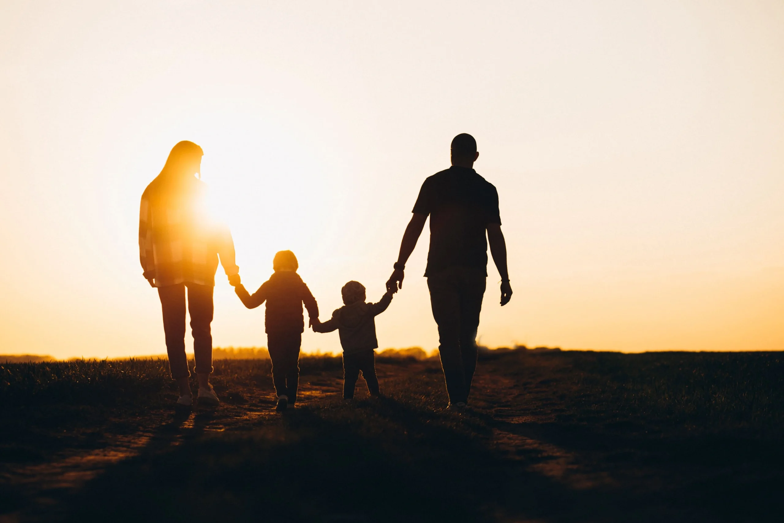 A family walking together at sunset, holding hands with their child, enjoying a peaceful moment outdoors. U.S. Citizen Can Petition for a Spouse, Parent, or Child Under 21