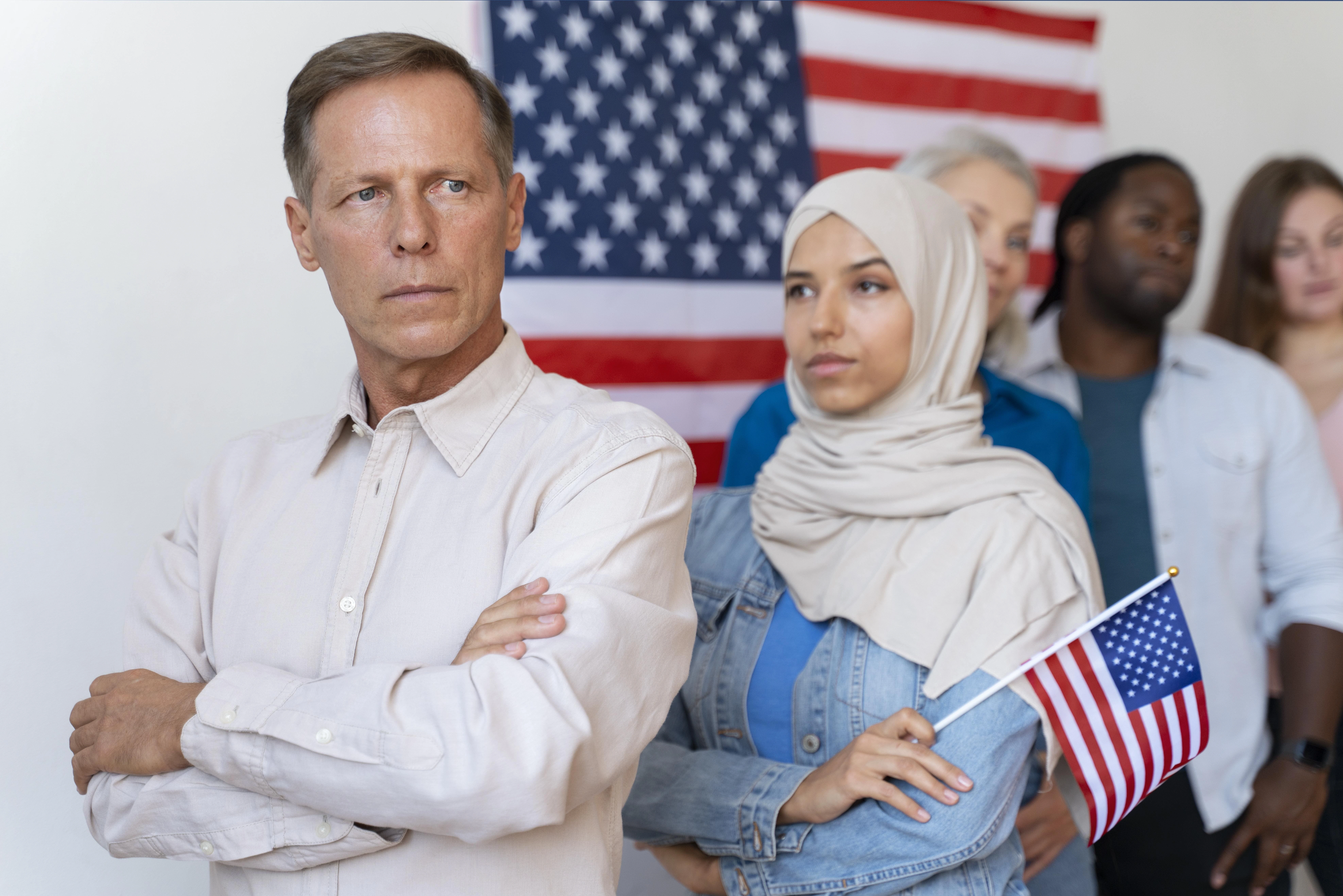 Diverse group of immigrants standing in front of an American flag, representing Temporary Protected Status (TPS), termination dates, and immigration policy updates in the United States for 2026.