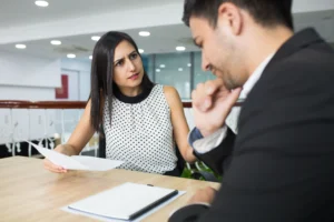 Una abogada sosteniendo documentos mientras conversa seriamente con su cliente en una oficina, explicando qué significa la desestimación de un caso de inmigración.