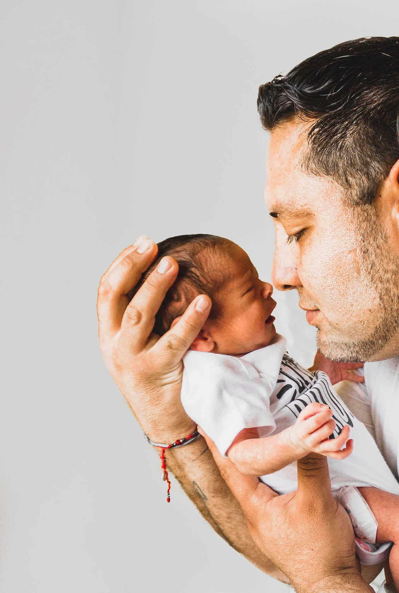 Close-up of a father gently holding his newborn baby, symbolizing hope and family unity, highlighting the importance of an immigration lawyer for DACA to secure a stable future for families.