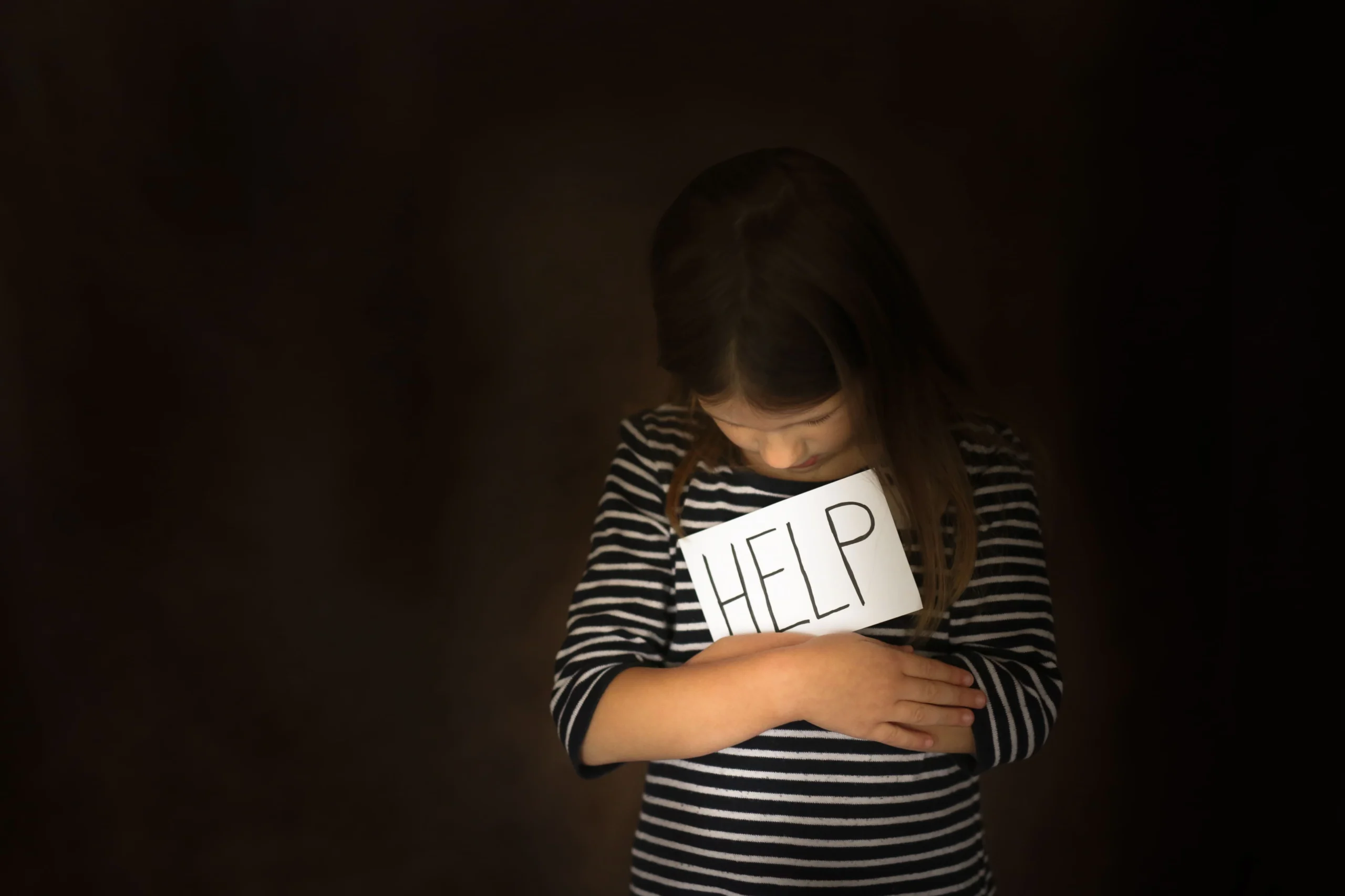 a-young-girl-holds-a-sign-reading-help-highlighting-the-need-for-support-under-vawa-requirements-in-los-angeles