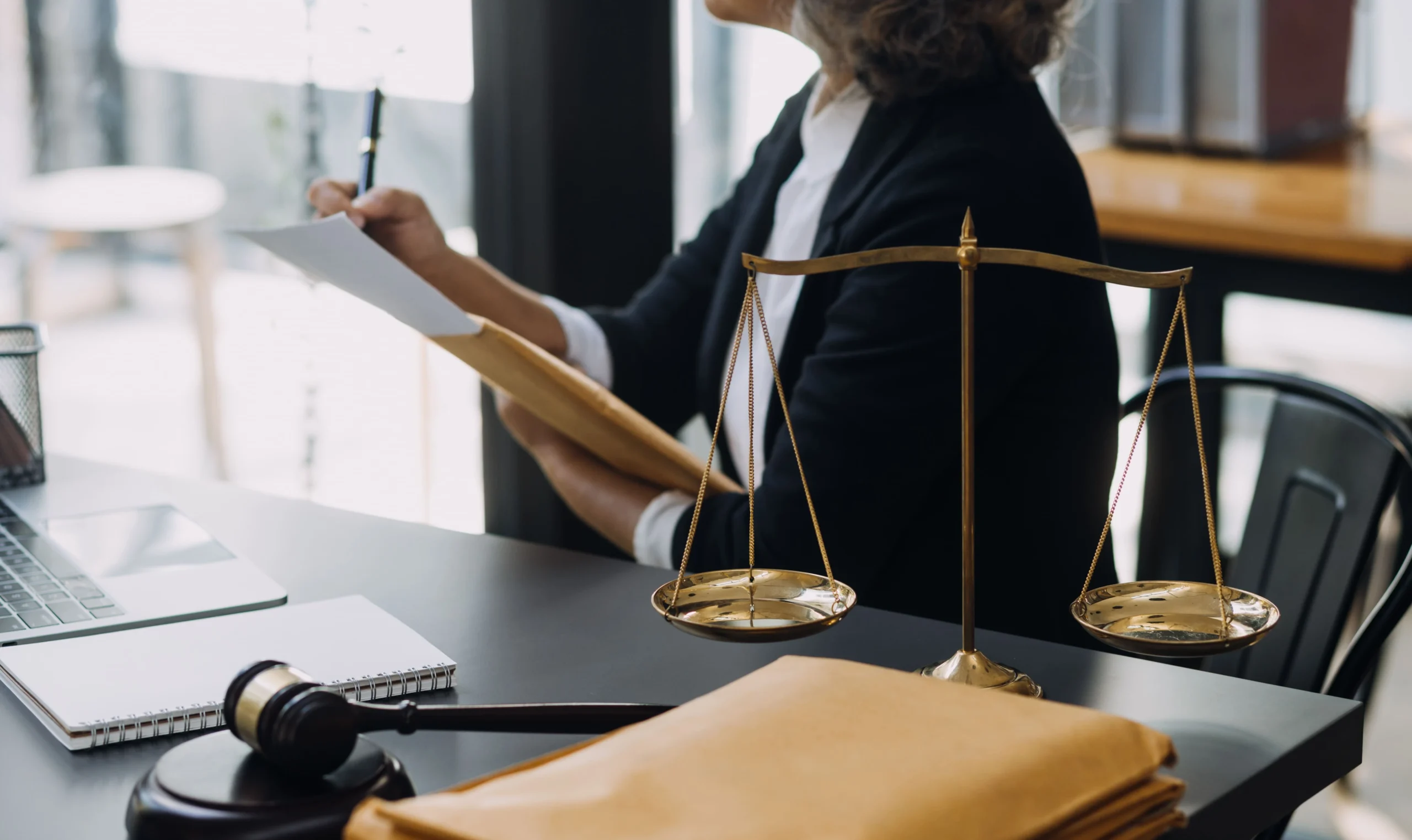 lawyer-at-desk-with-scales-of-justice-reviewing-papers-representing-clients-in-criminal-immigration-cases-in-los-angeles