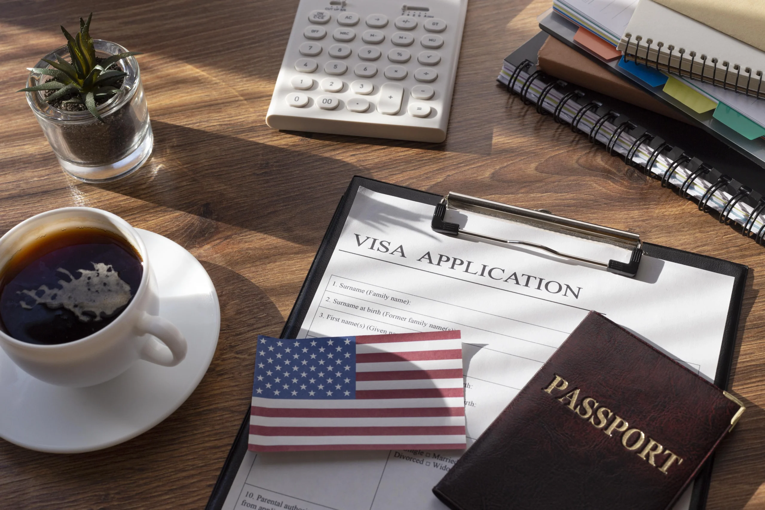 visa-application-documents-a-passport-coffee-and-a-calculator-arranged-on-a-desk-related-to-eb3-visa-requirements