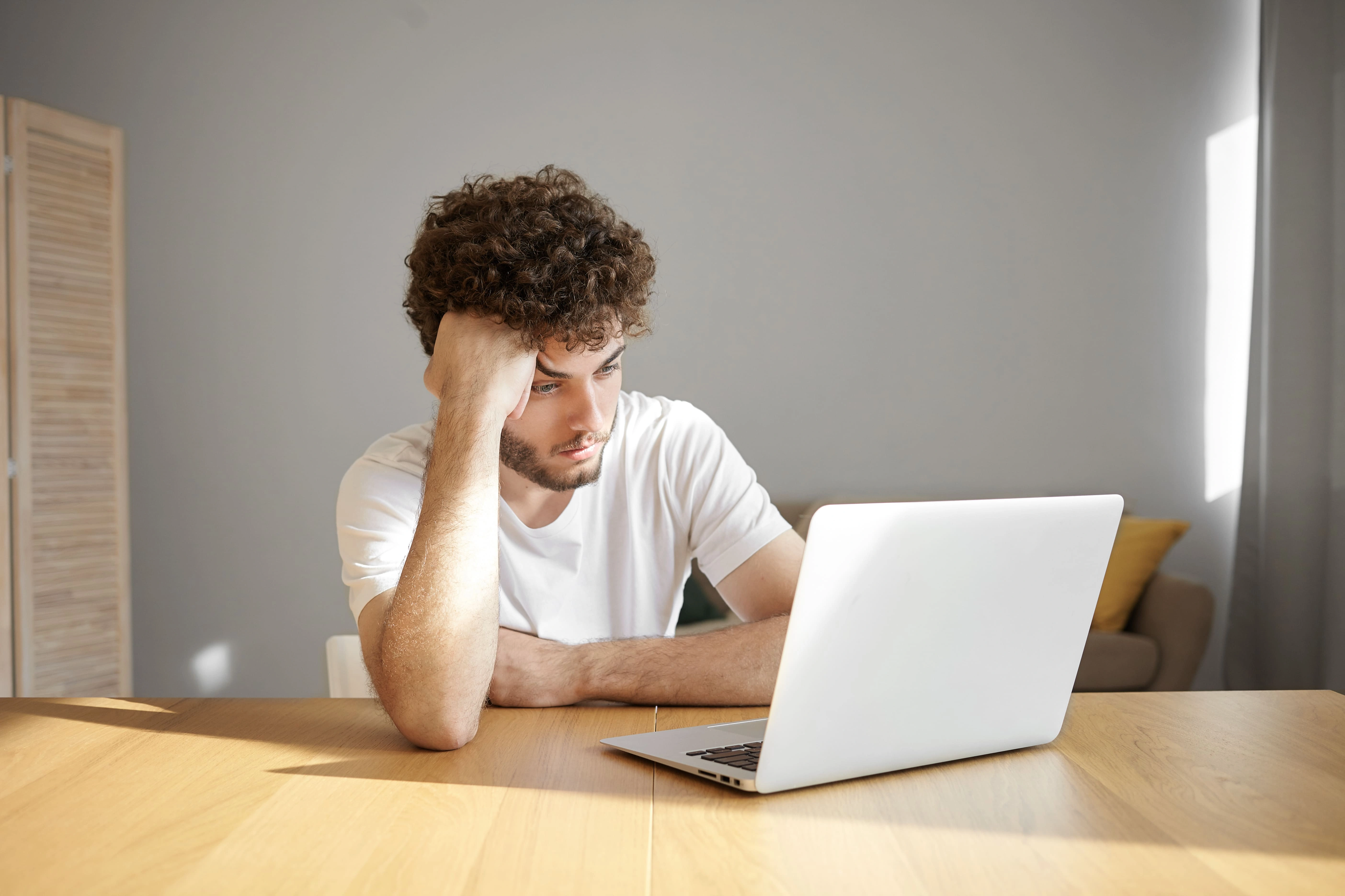Young H-1B worker looking stressed while reviewing immigration updates on a laptop after learning about new Trump rules affecting the H-1B to green card process